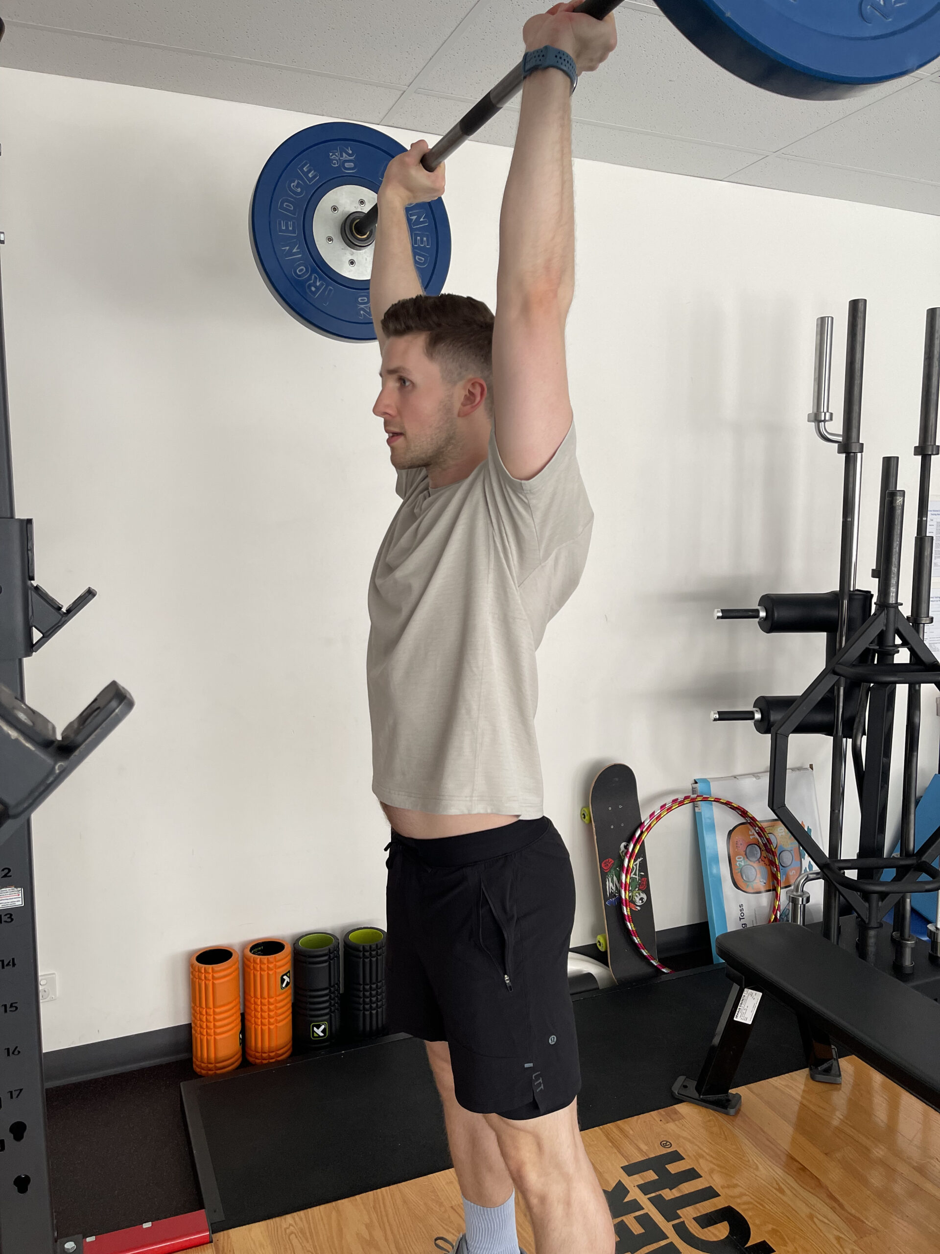 An athlete lifting weights with support from a sports physio in Adelaide